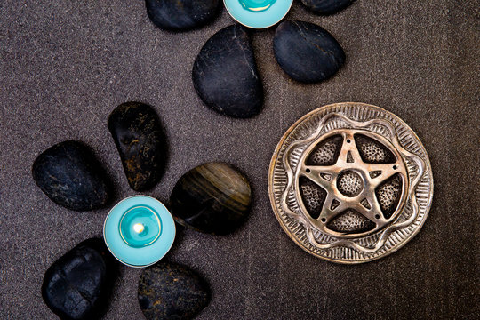 Turquoise candles with black rocks and silver pentagram on gray slate background