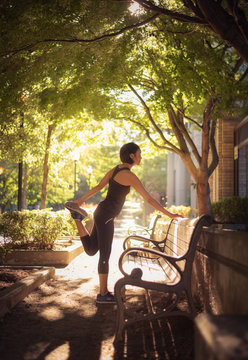 A runner stretches in a city park.
