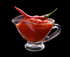 Red chili sauce in the sauce boat. With pepper.