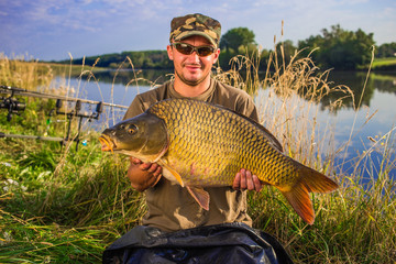 Happy angler with carp fishing trophy.Fish trophy