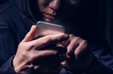 Hooded cyber crime hacker using mobile phone internet hacking in to cyberspace,online personal data...