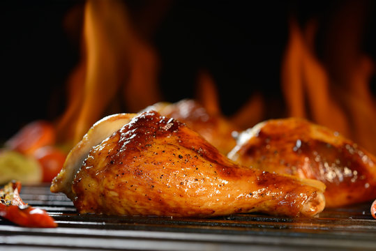Grilled chicken leg on the flaming grill