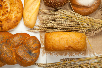 Assortment of baked bread on white wooden table background