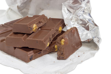 Pieces of the milk chocolate in open foil wrapper closeup