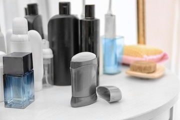 Deodorant for men and different hygiene items on shelf in bathroom