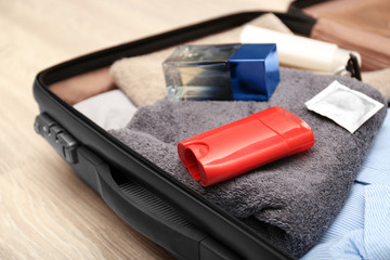 Suitcase with personal things and male hygiene accessories on floor, closeup
