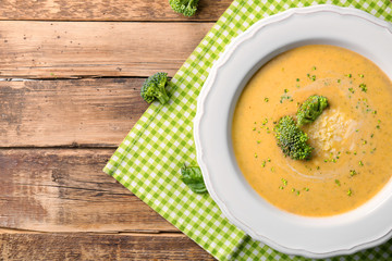Broccoli cheddar soup in bowl on wooden kitchen table