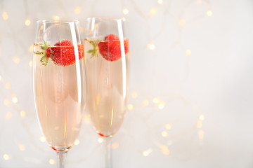 Glasses of delicious wine with strawberry against defocused lights