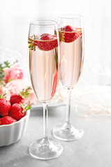Glasses of delicious wine with strawberry on table