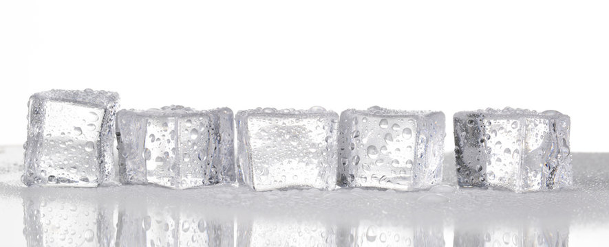 Melting ice cubes on glass table. On white background.


