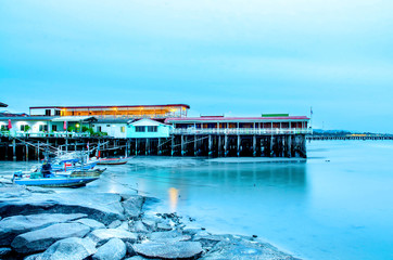 The sand beach and sea with fishing boat that parked on the beachfront with rock and reef in morning with sunrise, Beautiful sky with sea and fishing boat and rock with house in the seafront.