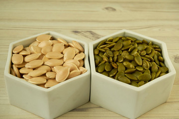 pumpkin seeds and peeled pumpkin seeds on the ceramic white bowl.