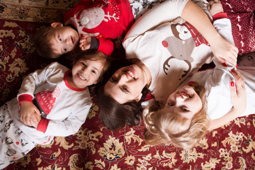 Happy family mother andand three her small children having fun lying  on a carpet.  Winter holiday Xmas and New Year.