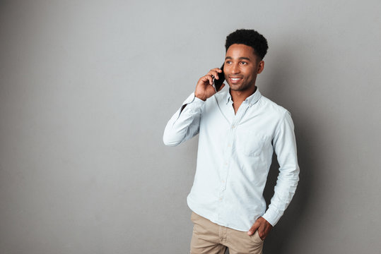 Attractive young african man talking on mobile phone while standing
