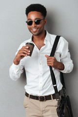 Man in sunglasses wearing a bag and holding coffee cup