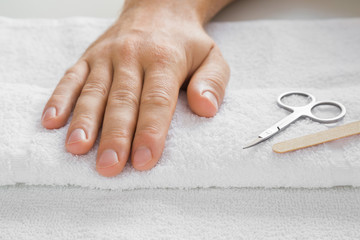 Cares about a man's hands nails. Manicure beauty salon. Scissors and nails file on the white towel.