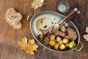 Roast beef steak with in copper pan on wooden table