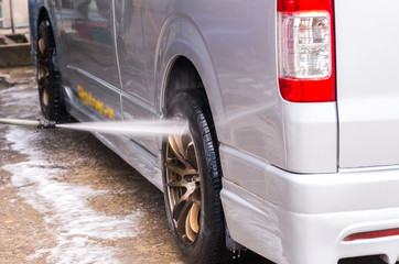 Van Car wash by high pressure cleaners, focus on the car's wheel
