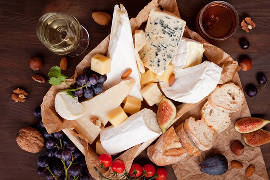 Variety of different cheese with wine, fruits and nuts. Camembert, goat cheese, roquefort, gorgonzolla, gauda, parmesan, emmental