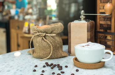 Cappuccino coffee cup on wood table with traditional coffee beans and grinder
