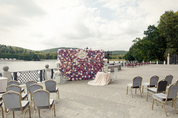 Wedding altar made of wall of pink and violet flowers stands before the lake