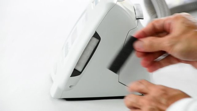 Man Hands Reassembling Air Filter To Air Inlet Of Cpap Main Unit,white Background,selective Focus.Replacing Disposable Filter  In White And Cleaning Washable Filter Is A Routine Maintenance Job.