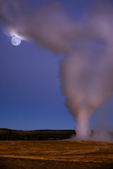 Old Faithful geyser and full moon