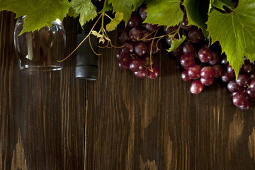 Grapes on a branch with leaves, a glass of young wine and fresh cheese on rustic wooden background....