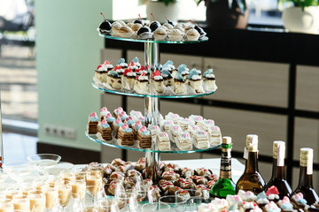 Tired glass dish with pieces of different cakes stands on a table