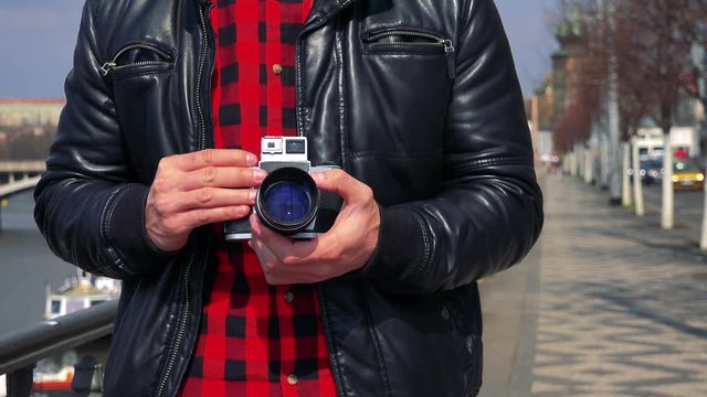 A man holds a camera against his chest in a street - closeup