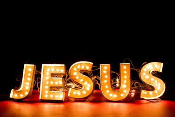 Jesus sign made with lights in a dark room over red floor