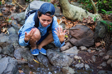 Beautiful woman is drinking water thirsty while hiking to travel.