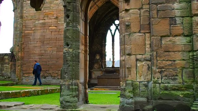 Tourists visiting the medieval ruins of The Holy Trinity Cathedral in Elgin, Scotland, UK, on a rainy day.
