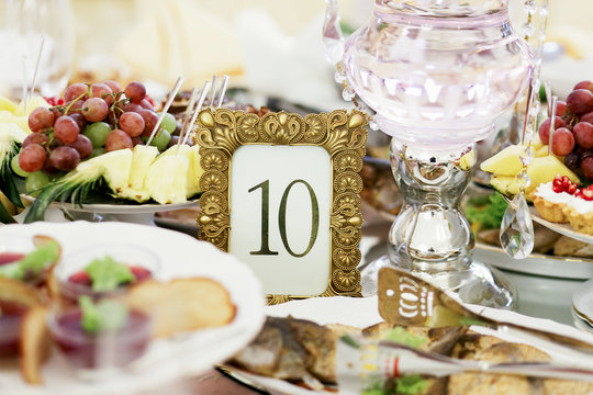 Number 10 put in a golden frame stands among white plates with fish and fruits