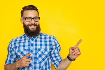Cheerful hipster pointing on side