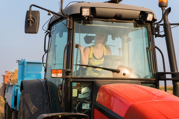 Beautiful, young farmer girl is driving tractor