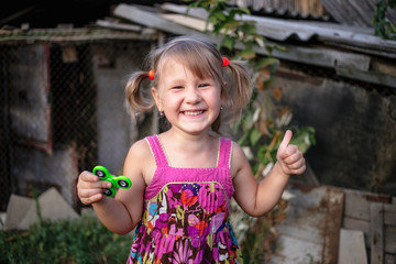 Happy little rural girl with a spinner in her hand holds a thumbs up.