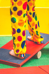 child with clown costume standing on a seesaw