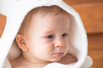 Baby wearing white towel. Little baby boy relaxing in bed after bath or shower.