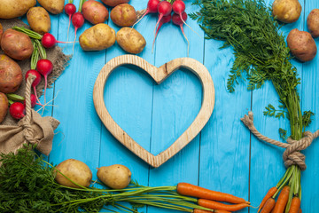Potatoes, carrots, radishes and hearts on a blue background