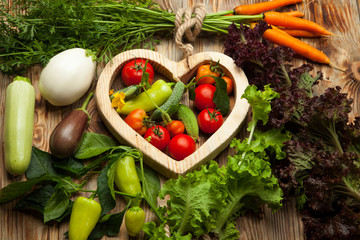 Vegetables in the heart on a rustic wooden background