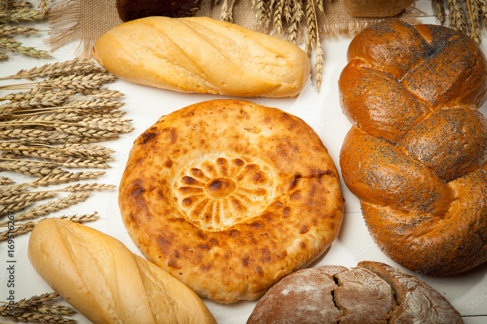 Wall mural assortment of baked bread on white wooden table background