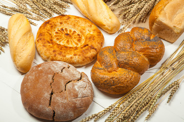 Assortment of baked bread on white wooden table background