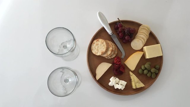Woman hands serving cheese platter with red wine
