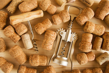 A lot of wine corks and two corkscrews on the wooden background, top view.