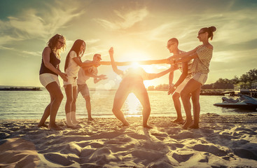 Friends funny game on the beach under sunny sky with clouds at s