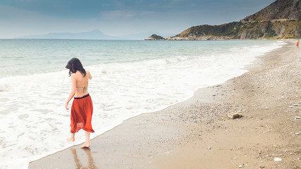 Young woman walking alone in barefoot at the shore