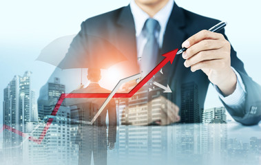 Businessman point at increasing graph and decreasing broken graph with city background