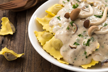 Plate of ravioli with cream sauce on wood table