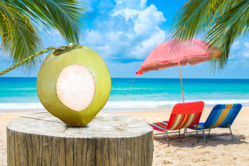 Text space on the coconut placed on timber and Sandy summer beach background.